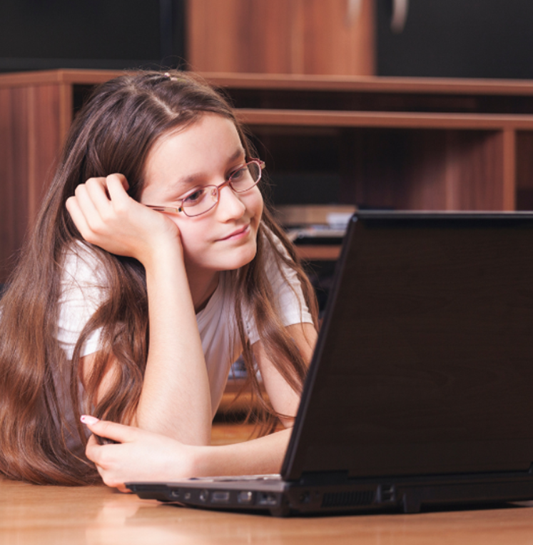 Girl with headphones talking to her teacher on a laptop