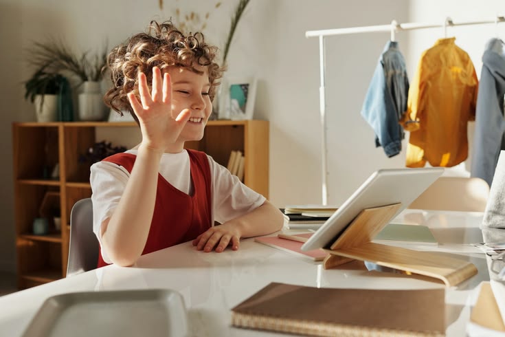 Young student waving at a laptop during an online class